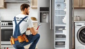 A professional appliance repair technician from Central Minnesota Appliance Repair working on a stainless steel refrigerator in a modern kitchen, surrounded by other appliances like a washer, dryer, oven, and dishwasher, highlighting the range of repair services offered.